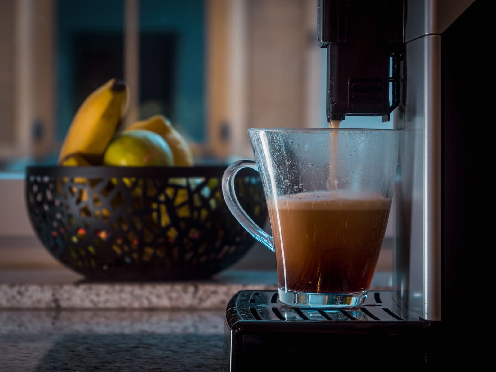 An espresso machine pulling a shot into a cup on a home kitchen counter